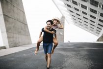 Joven hombre dando a su novia un paseo a cuestas - foto de stock