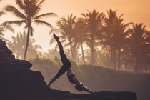 Indonesien, Bali, Frau praktiziert Yoga an der Küste in der Dämmerung — Stockfoto