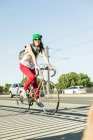 Giovane donna in bicicletta sul marciapiede in strada — Foto stock