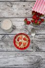 Granola with popped amaranth and strawberries in bowl on grey wood with ingredients — Stock Photo