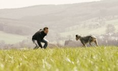 Man exercising with dog on meadow — Stock Photo