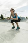 Молодая женщина тренируется в скейт-парке — стоковое фото