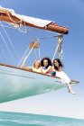 Three young women on a sailing trip sitting on bow — Stock Photo