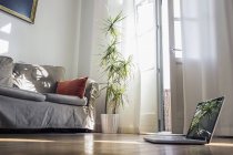 Laptop steht auf dem Holzboden eines Wohnzimmers — Stockfoto