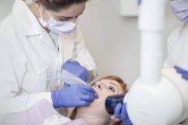 Dentista inspeccionando los dientes de un paciente - foto de stock