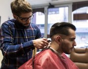 Парикмахер бреет волосы молодого человека в парикмахерской — стоковое фото