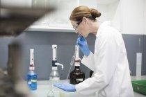 Femme scientifique travaillant en laboratoire avec des pipettes — Photo de stock