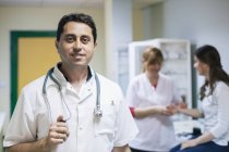 Портрет врача с пациентом и медсестрой на заднем плане — стоковое фото
