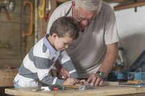 Дедушка и внук работают с деревом в гараже — стоковое фото