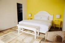 Indonesia, Bali, dormitorio con pared amarilla y mesitas de noche amarillas de una villa de vacaciones - foto de stock