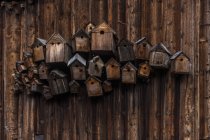 Different wooden birdhouses hanging on wooden wall — Stock Photo