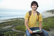 Uomo sorridente con mappa sulla costa — Foto stock