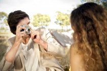 Man photographing his girlfriend outdoors — Stock Photo
