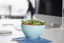 Bowl with garnished salad on a desk in an office — Stock Photo