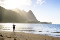 USA, Hawaii, Hanalei, woman standing on Haena Beach, View to Na Pali Coast in the evening light and woman standing on the beach — Stock Photo