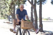 Smiling senior man balancing on bicycle — Stock Photo