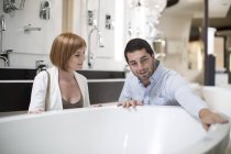 Venditore negozio bagno che mostra vasca da bagno al cliente femminile — Foto stock