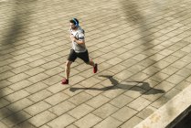 Giovane uomo di jogging su strada con cuffie — Foto stock