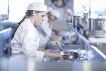 Teenage girl cooking in canteen kitchen — Stock Photo