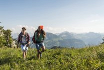 Áustria, Tirol, Tannheimer Tal, jovem casal caminhando no prado alpino — Fotografia de Stock