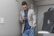 Hombre de negocios mirando su teléfono inteligente en una habitación de hotel - foto de stock