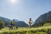 Österreich, Tirol, Tannheimer Tal, junges Paar auf Mountainbikes in alpiner Landschaft — Stockfoto