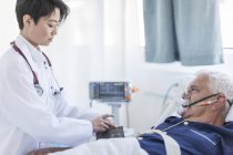 Medico che prende la pressione sanguigna dell'uomo anziano con maschera di ossigeno in un ospedale — Foto stock
