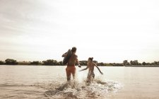 Young couple running with inner tube in river — Stock Photo