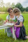 Young girl wearing dirndl learning to draw plants — Stock Photo
