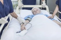 Ragazza sdraiata nel letto d'ospedale con i chirurghi intorno — Foto stock
