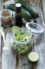 Einmachglas mit frisch geschnittenen Zucchini mit Limetten und Gewürzen auf Holz — Stockfoto
