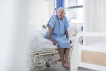 Старший пацієнт сидить на лікарняному ліжку — стокове фото