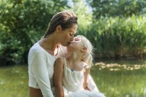 Mutter und Tochter küssen sich an einem See — Stockfoto