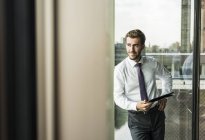 Lächelnder junger Geschäftsmann mit digitalem Tablet — Stockfoto