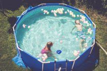 Мальчик и девочка в бассейне в окружении воздушных шаров — стоковое фото