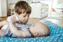 Baby girl and brother cuddling at home — Stock Photo