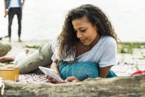 Розслаблена молода жінка з цифровим планшетом на відкритому повітрі — стокове фото
