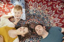 Portrait of parents and little son lying on a Persian rug at home — Stock Photo
