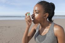 Молодий бігун, використовуючи астму інгалятор на пляжі — стокове фото