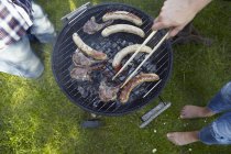 Чоловік готує ковбаски барбекю в парку — стокове фото