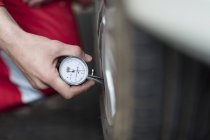 Mecánico de automóviles en el trabajo en el garaje de reparación, manómetro de neumáticos - foto de stock