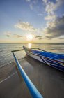 Indonesia, Bali, Jimbaran, Barco de pesca tradicional en la playa al atardecer - foto de stock