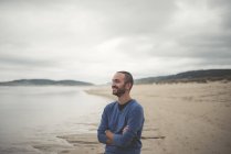Spanien, Fähre, Porträt eines lächelnden Mannes mit verschränkten Armen am Strand — Stockfoto