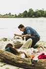 Young couple having a barbecue by the riverside — Stock Photo