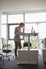 Young man in office working at adjustable desk — Stock Photo