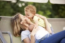 Young mother with her two little daughters on a canopy swing — Stock Photo