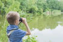 Boy with binoculars watching animals — Stock Photo