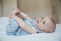 Baby girl lying on back on bed — Stock Photo