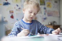 Retrato de un niño rubio pintando con acuarelas - foto de stock