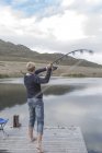 Joven pescando en un lago - foto de stock